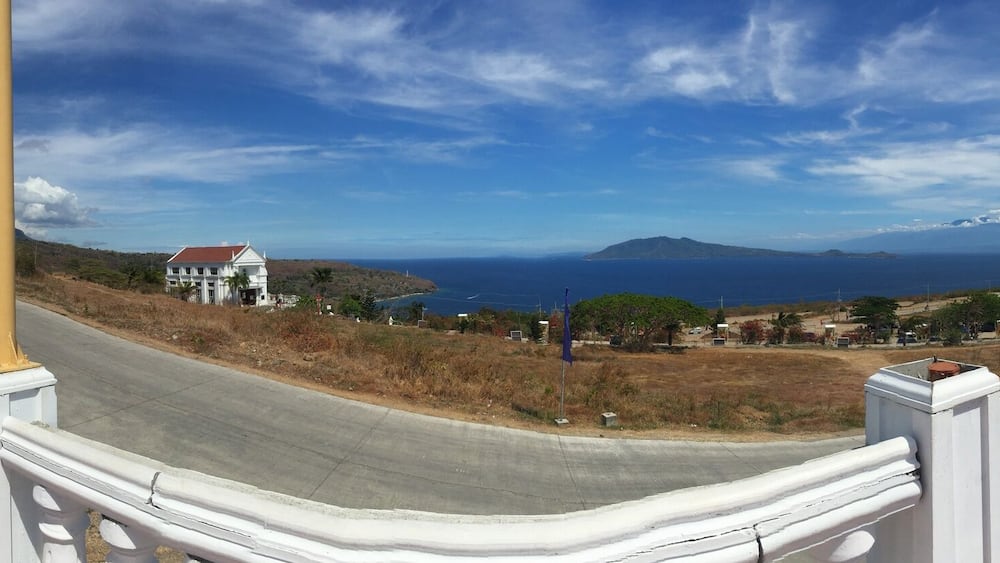A staircase leading to a coastal view with a statue, a white building, and a clear sky.
