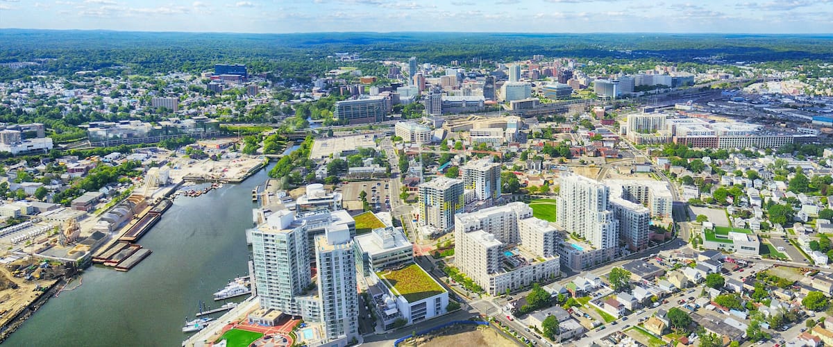 A cityscape with a river, modern buildings, and green spaces.