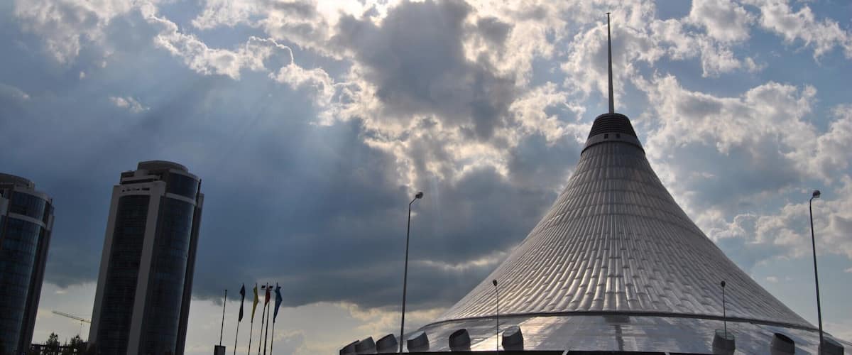 Sun rays beam down around Khan Shatyr just moments before a thunder storm.