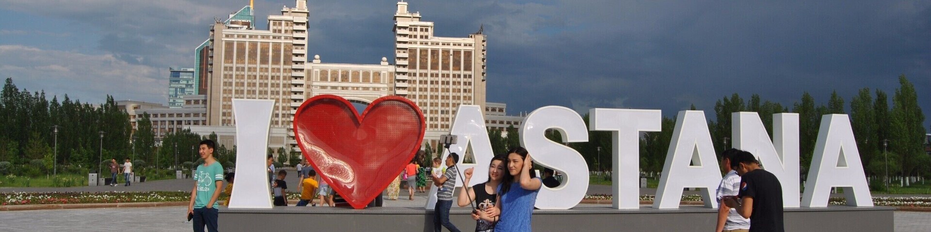 Un gran letrero con la inscripción 'I ♥ ASTANA' y un símbolo de corazón, con gente de pie delante.