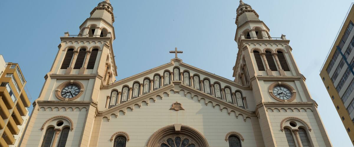 A large church with two towers, each with a clock and a cross at the top.