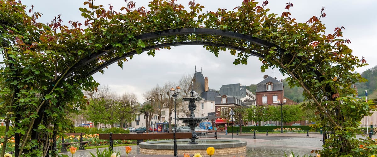 A garden with a fountain, colorful flowers, and a historic building in the background.