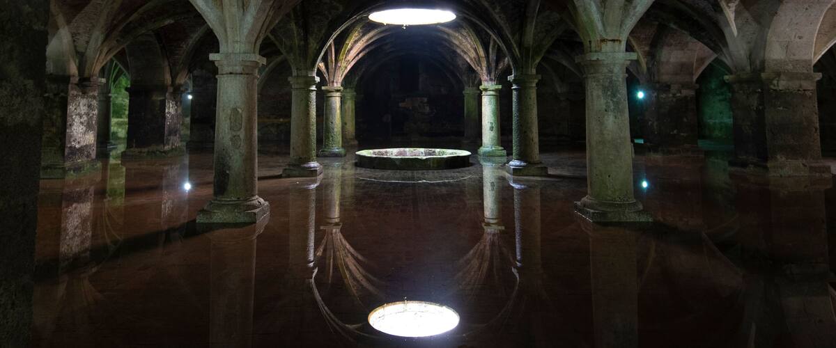 A dimly lit underground chamber with arched ceilings and columns.