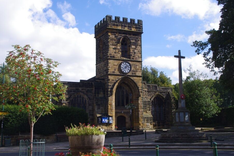 A historic church with a clock tower and a cross monument.