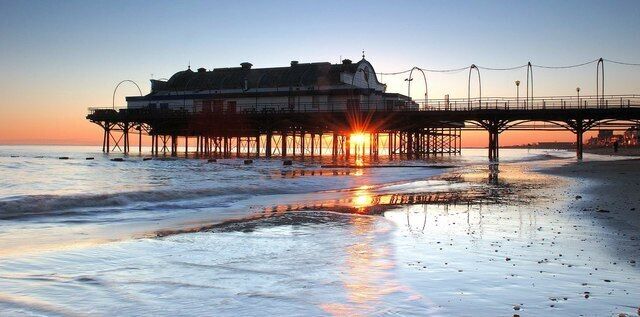 A pier extending into the ocean at sunset with a building on it.