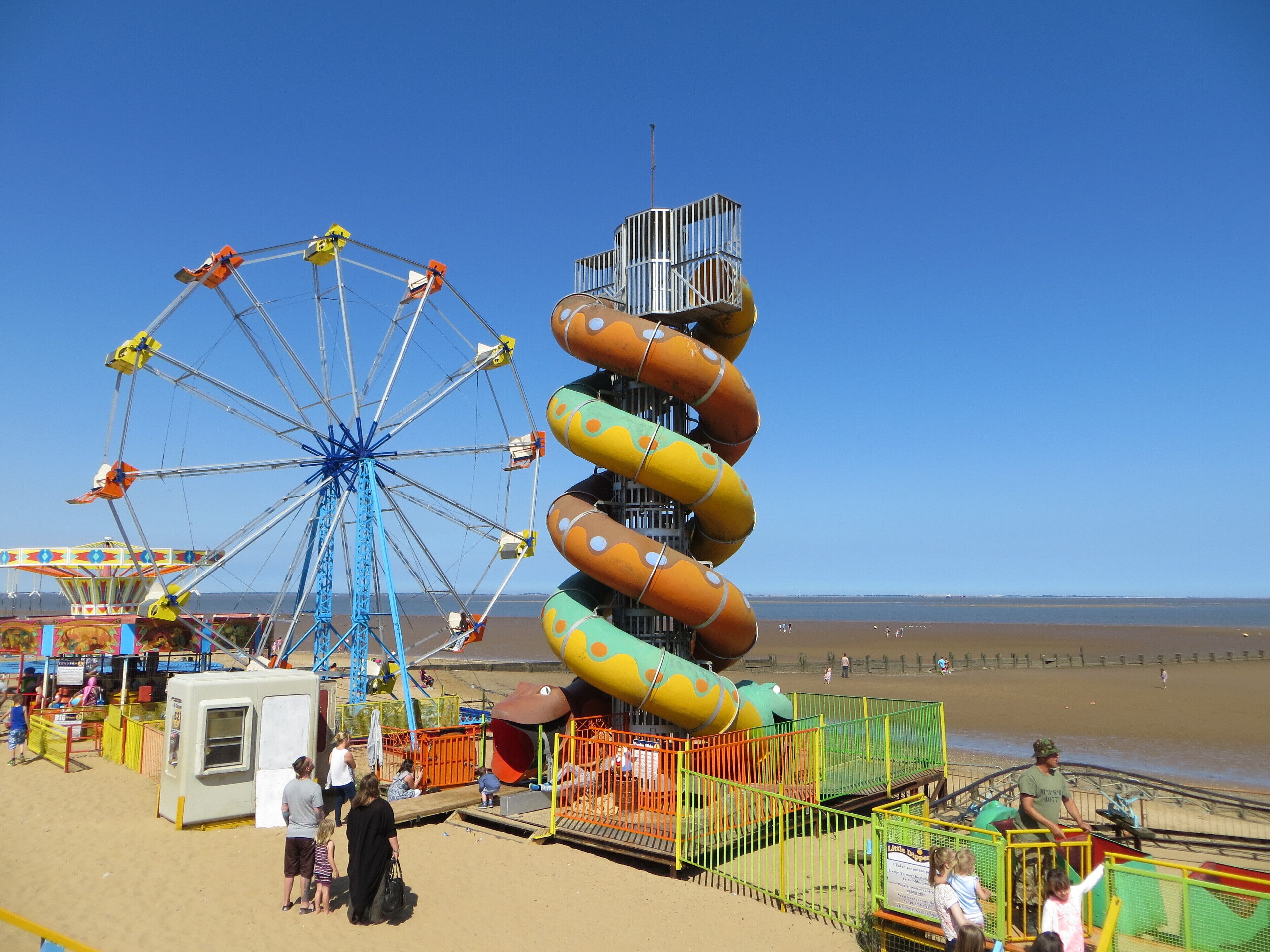 A beach with a large Ferris wheel and a spiral slide.