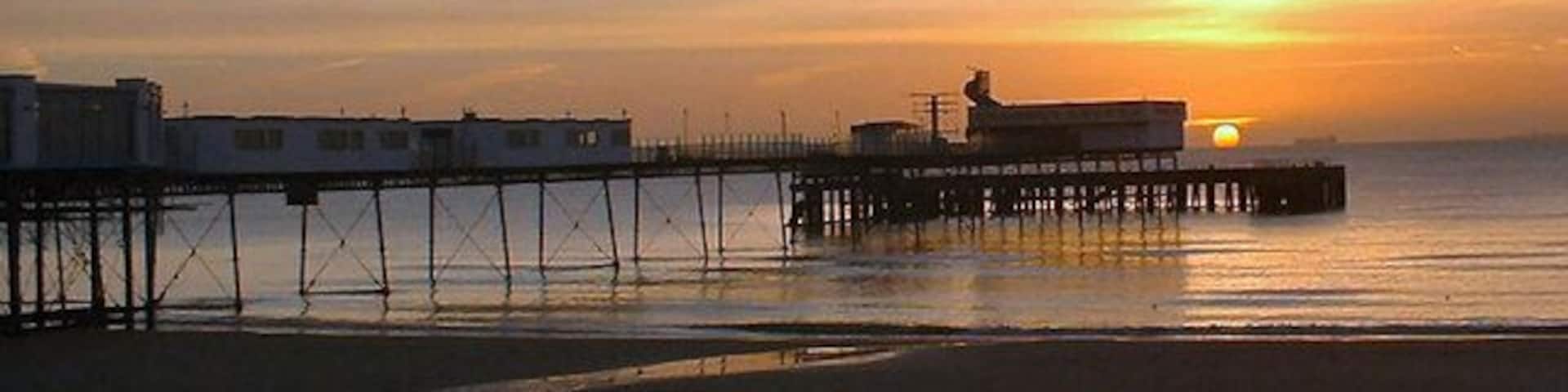 A pier extending into calm waters at sunset.