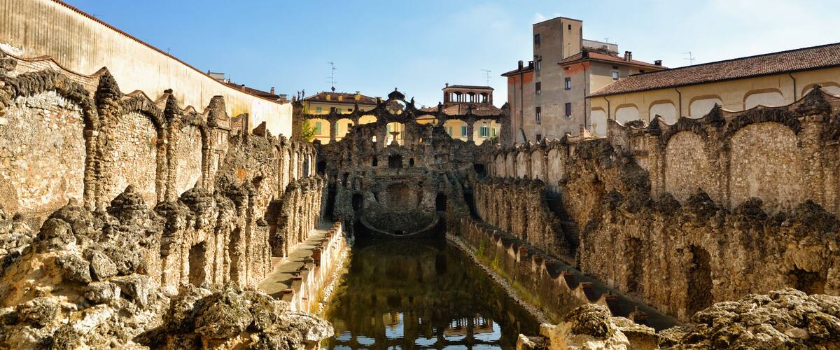 A historic stone bridge over a canal, surrounded by ancient walls and buildings.
