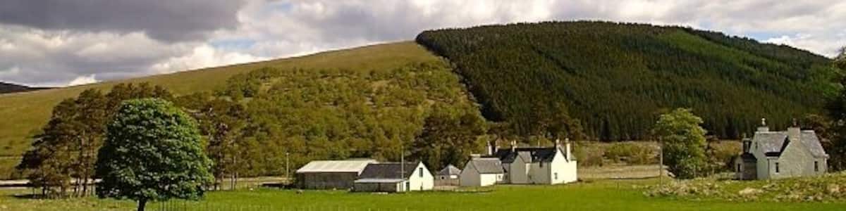 Un paysage rural avec une rivière, des maisons et une colline en arrière-plan.