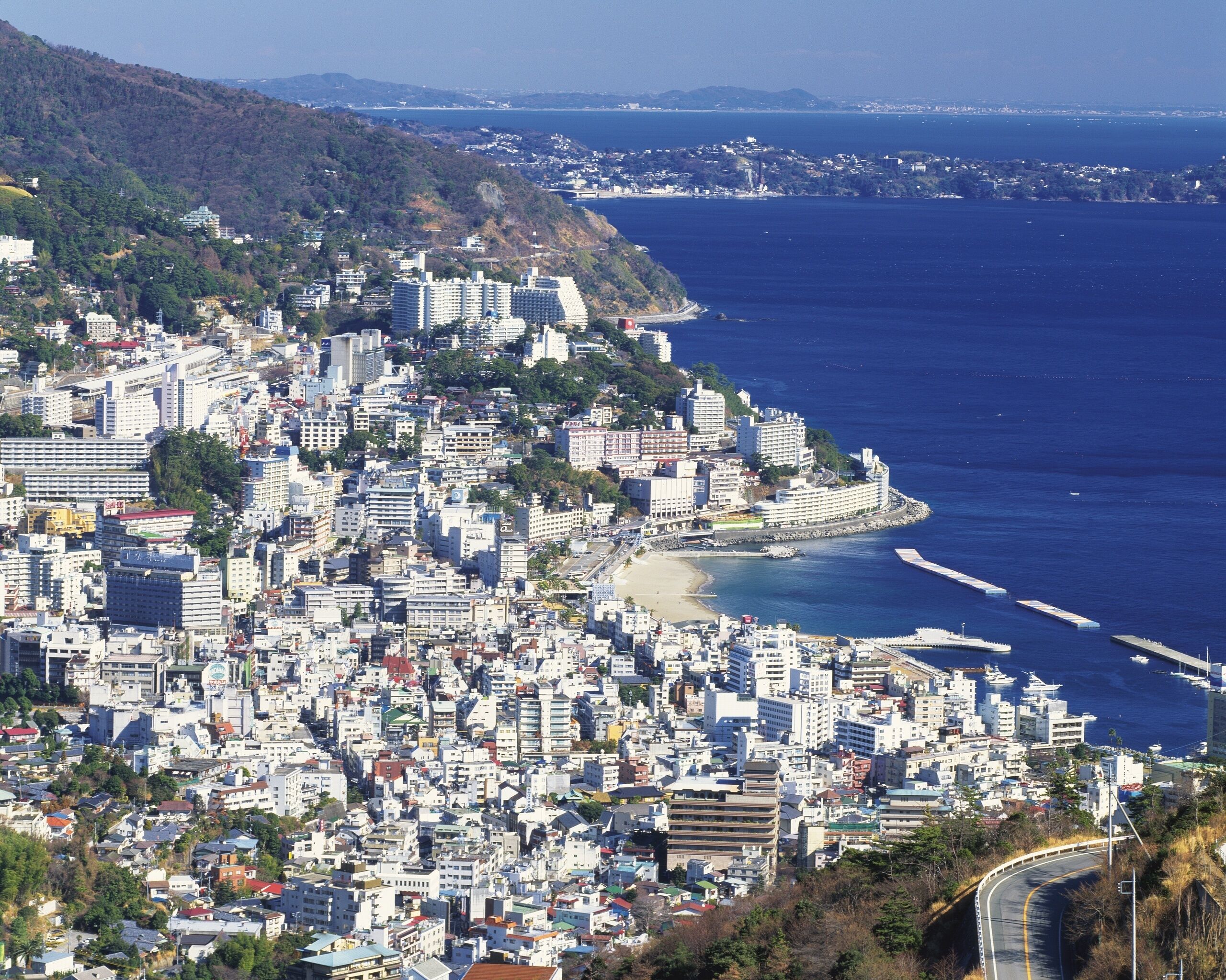 A coastal city with dense urban development, a beach, and a clear view of the ocean.