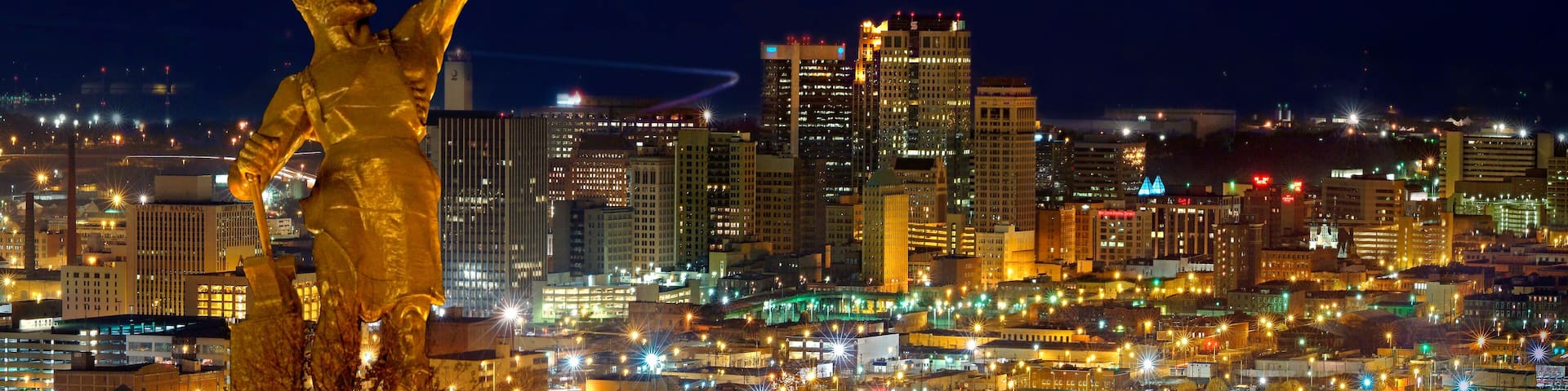 Birmingham city night view with Vulcan monument illuminated above urban landscape