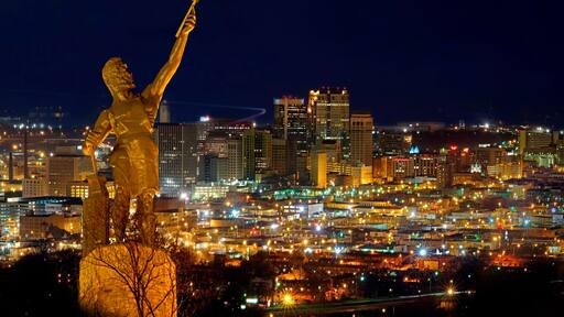Birmingham city night view with Vulcan monument illuminated above urban landscape