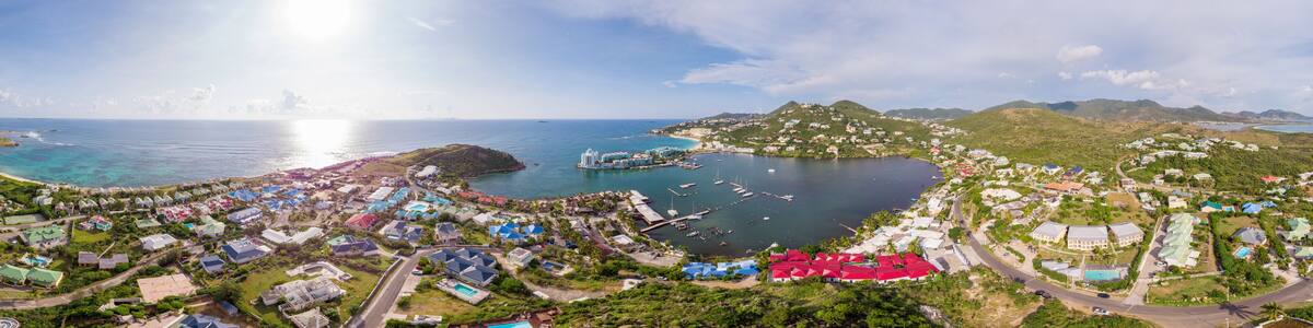 A coastal town with a marina, green hills, and colorful houses.