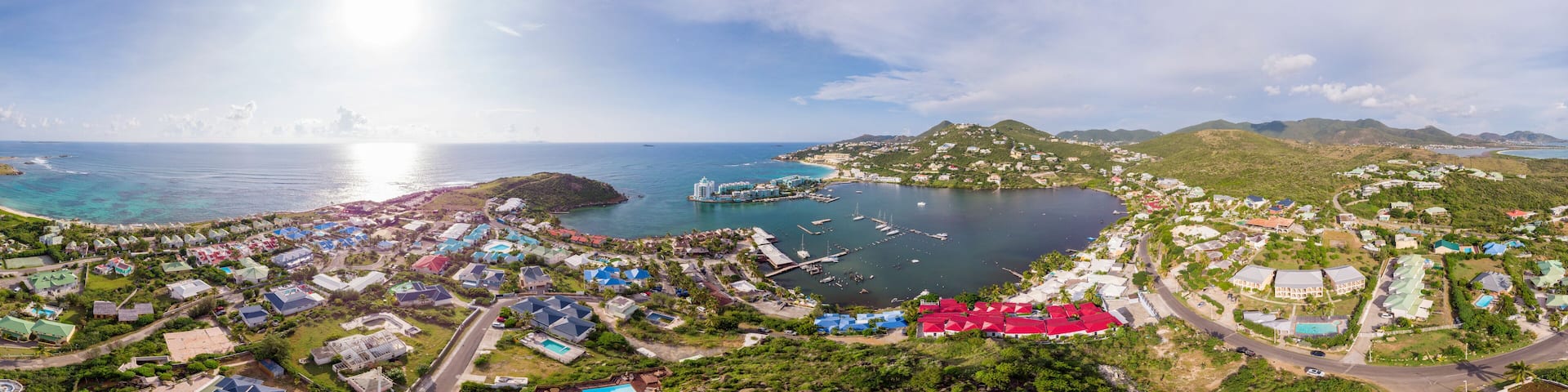 A coastal town with a marina, green hills, and colorful houses.