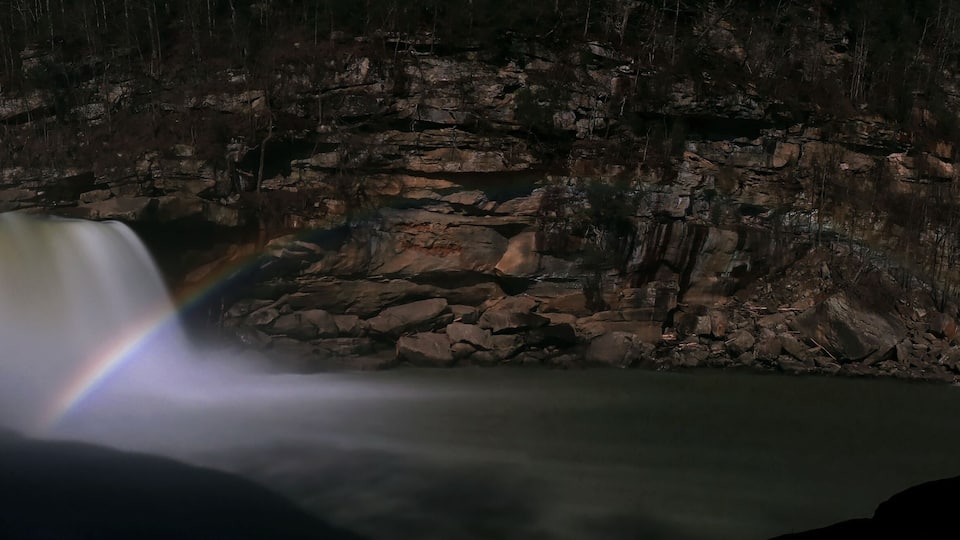 A waterfall with a rainbow at night.