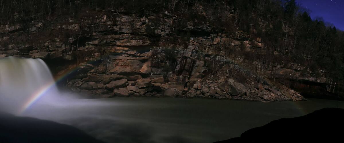 A waterfall with a rainbow at night.