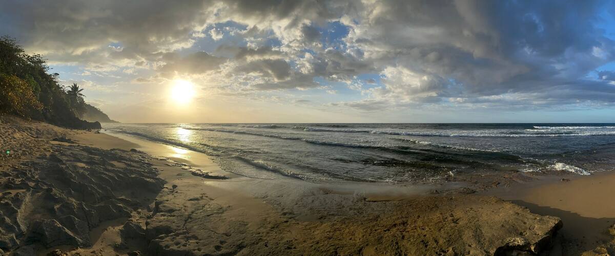 A beach with waves, rocky terrain, and a clear sky.