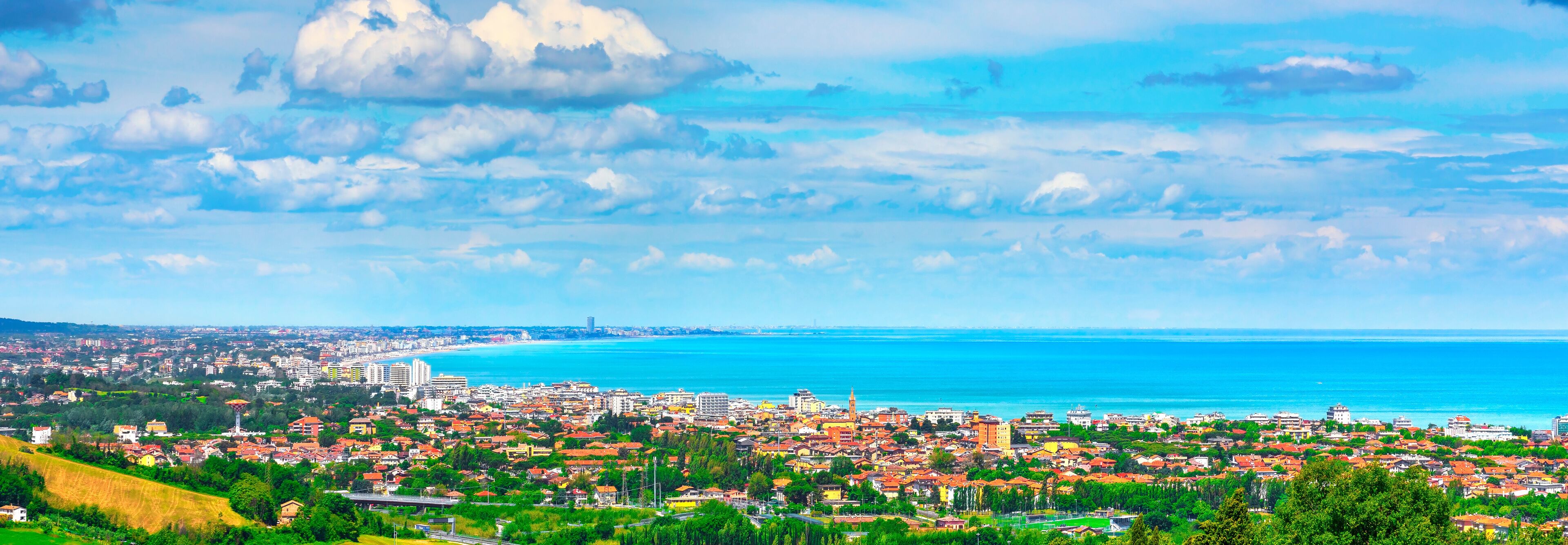 A coastal city with a view of the sea, buildings, and a prominent tower.