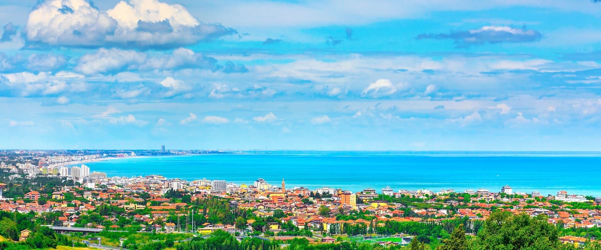 A coastal city with a view of the sea, buildings, and a prominent tower.