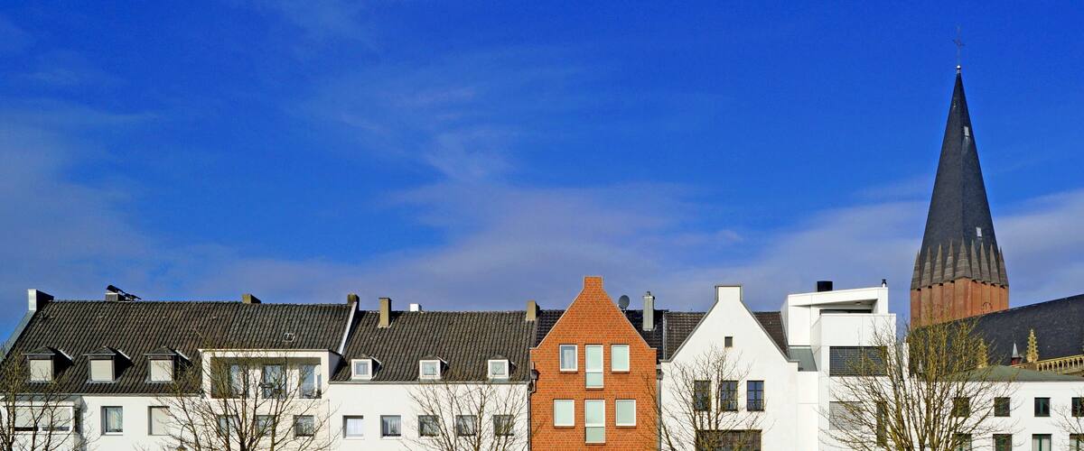 A row of traditional European houses with a prominent church steeple in the background.