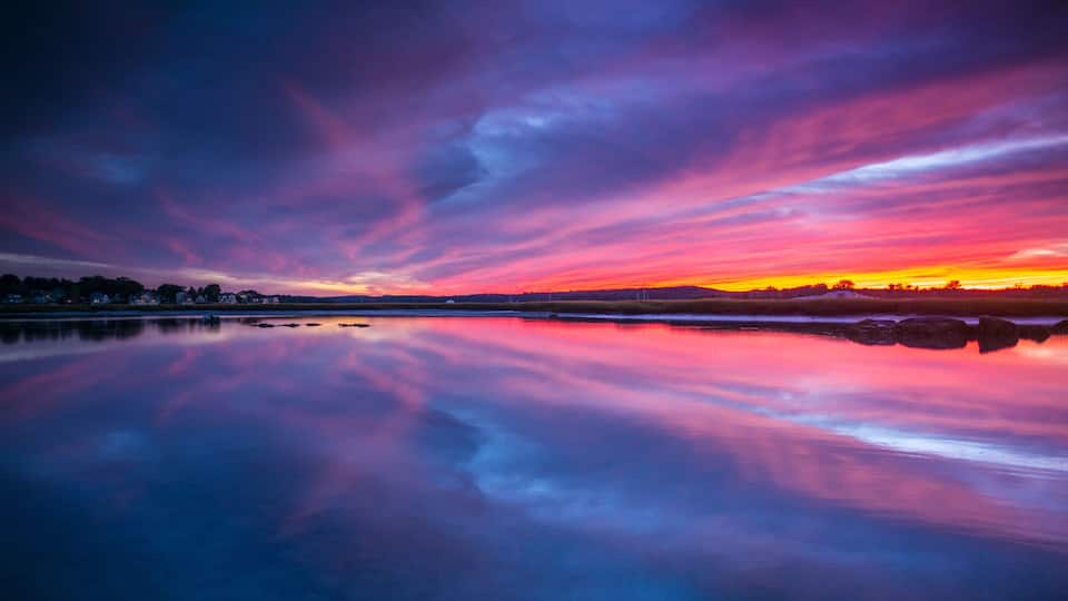 A sunset over a calm lake with vibrant sky colors reflecting on the water.