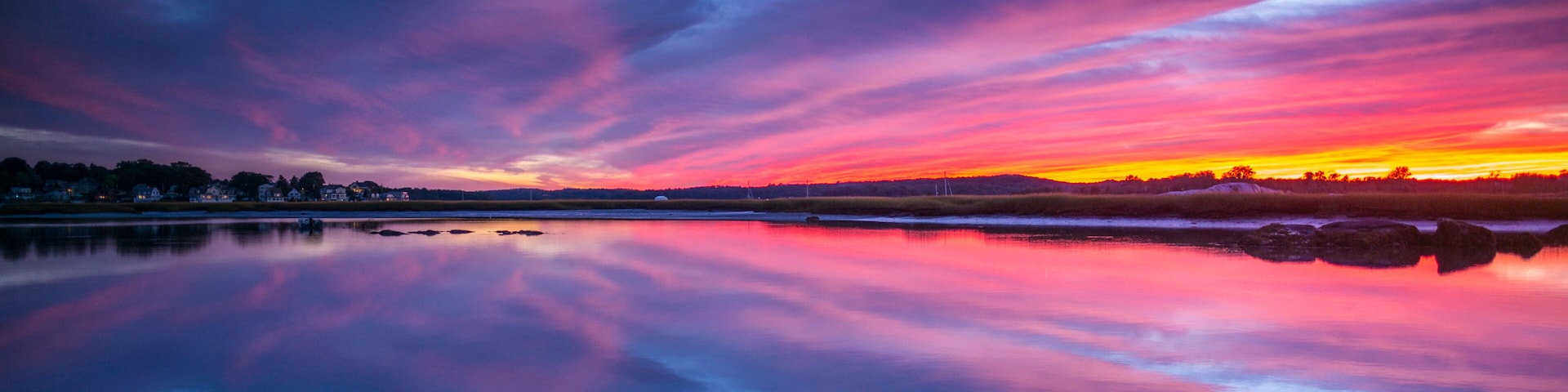 Un atardecer sobre un lago tranquilo, con colores vibrantes del cielo reflejados en el agua.