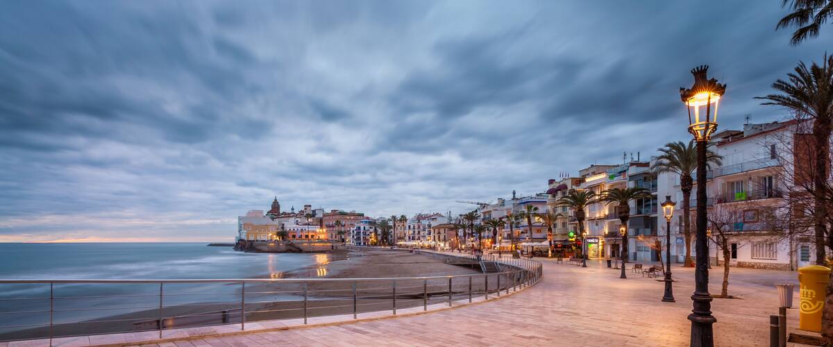 A coastal promenade with a sea view, a promenade with a railing, and buildings along the waterfront.