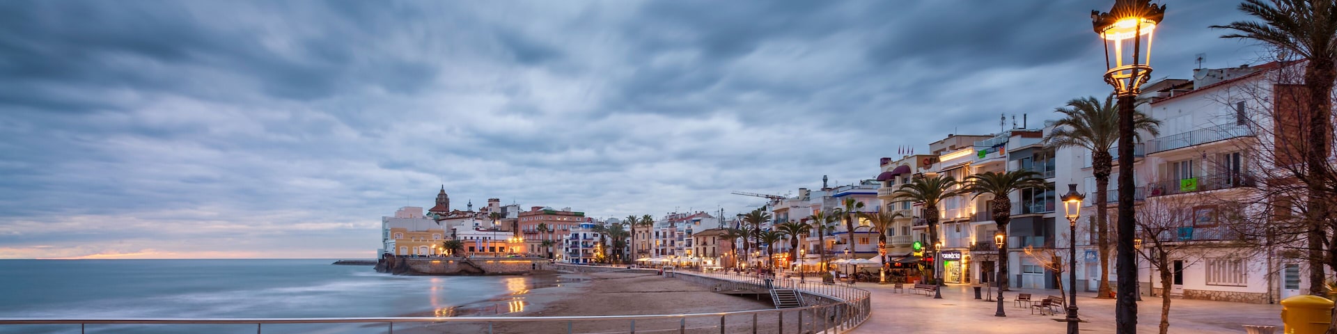 A coastal promenade with a sea view, a promenade with a railing, and buildings along the waterfront.