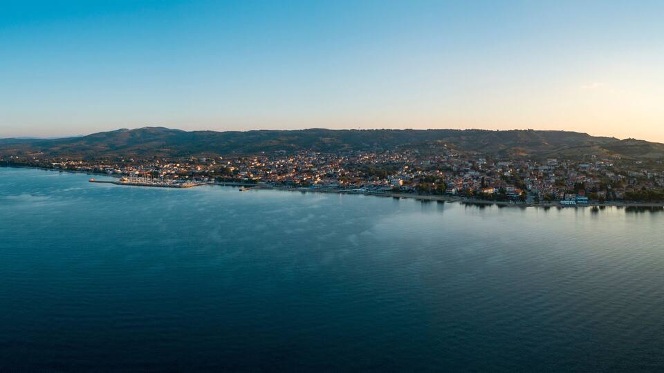 A coastal cityscape with a harbor, buildings, and hills in the background.