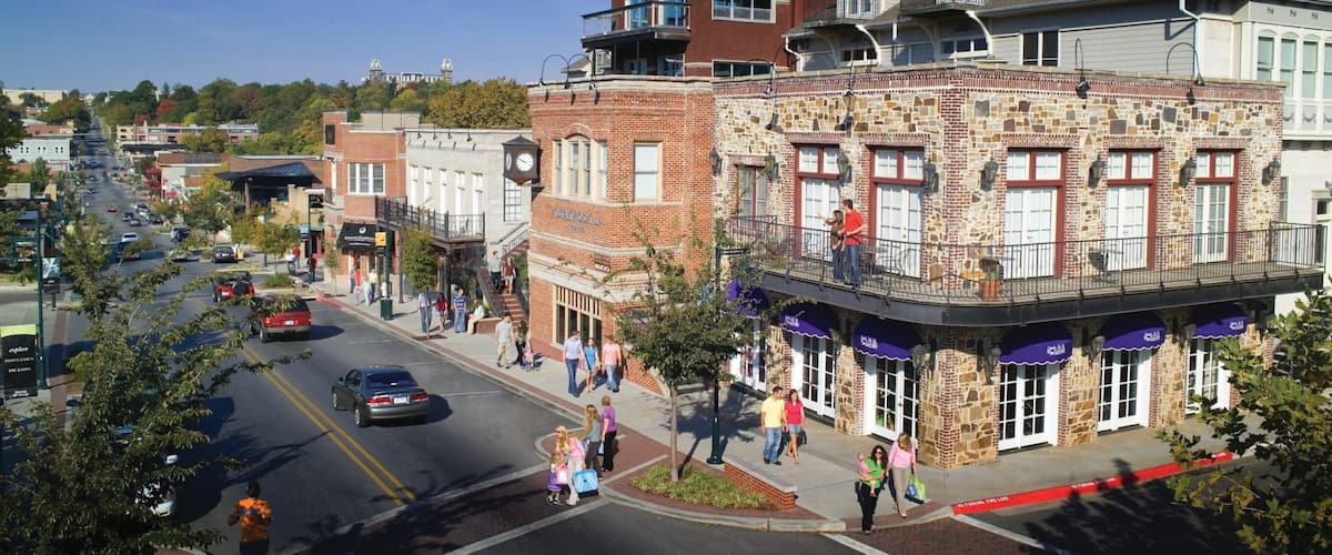 A street lined with historic buildings, a clock tower, and pedestrians.