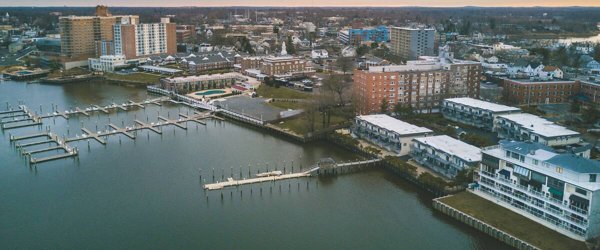 A waterfront cityscape with a marina, residential buildings, and a prominent clock tower.