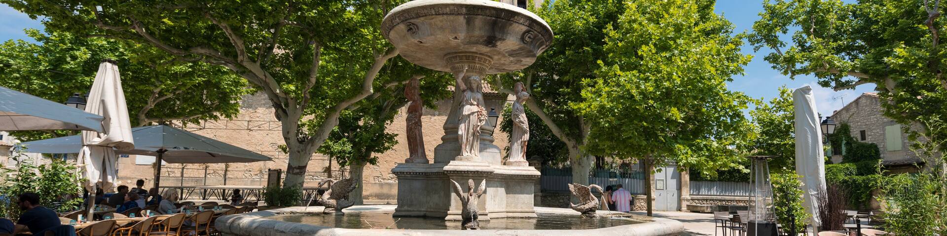 Village square with fountain and restaurant of Maussane les Alpilles. Buches du Rhone, Provence, France; Shutterstock ID 1157625601; Purchase Order: SP-1394 HA Batch 3 Part 1; Order Number: ; Client/L
