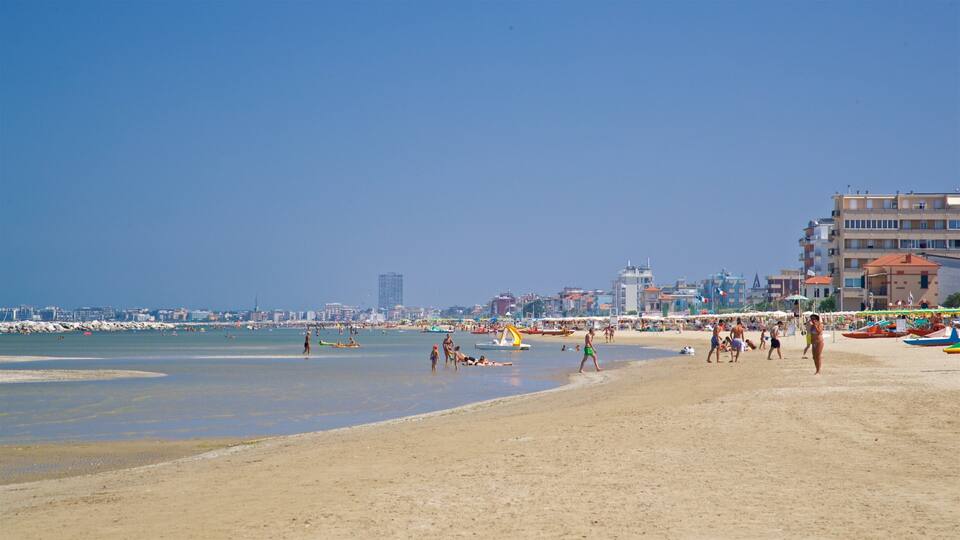 Platja sorrenca amb persones, vaixells i edificis al fons.