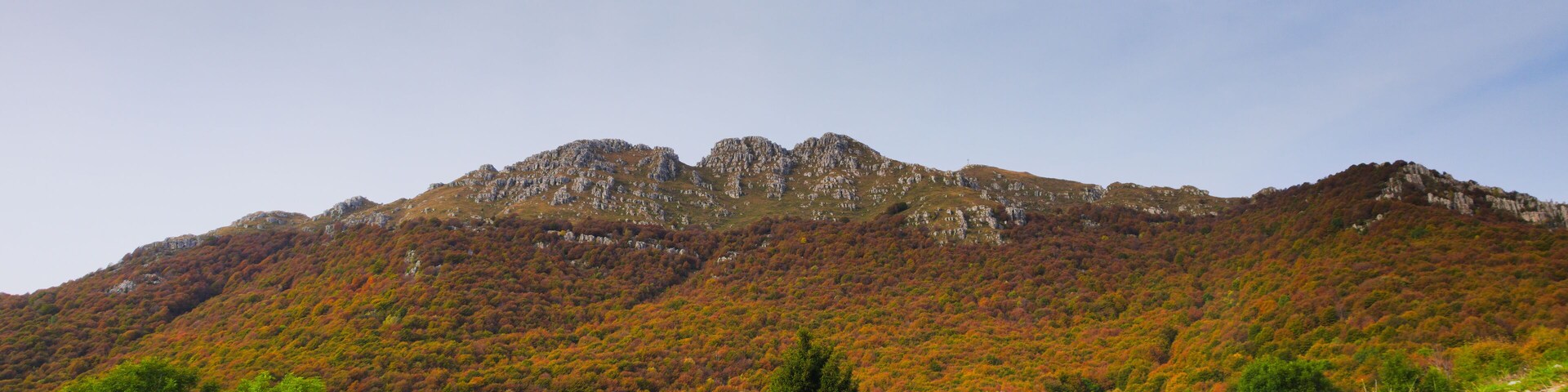 A mountain landscape with autumn foliage, rocky terrain, and a clear sky.