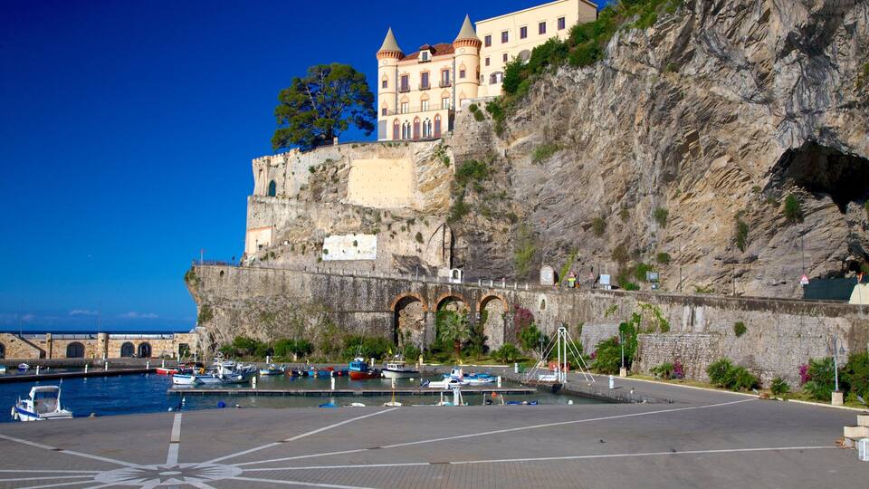 A historic building perched on a cliff overlooking a marina with boats.
