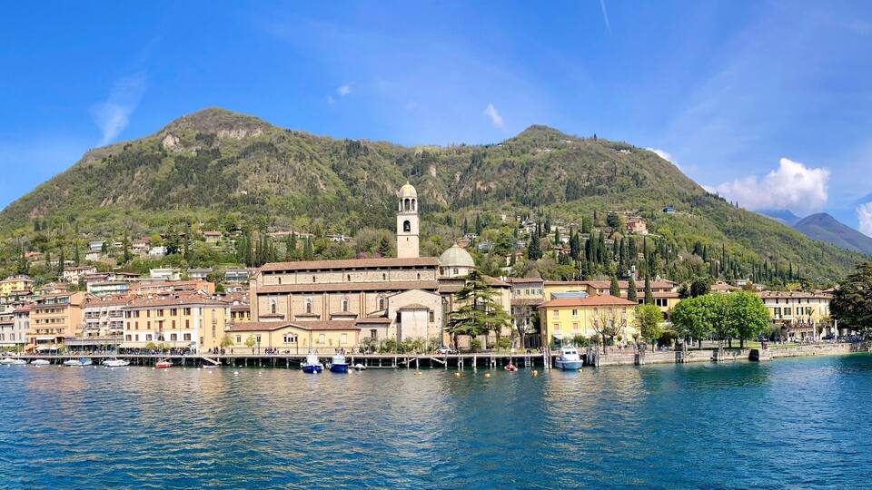 A lakeside town with historic buildings, a prominent church, and a mountain backdrop.