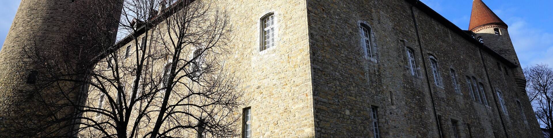 A historic stone building with two prominent towers and a clear blue sky.