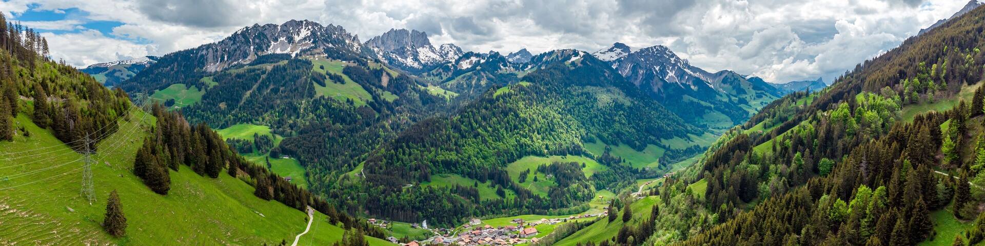 View on alps mountains, green fields, cloudy sky by Jaun, Jaunpass. Canton Fribourg, Freiburg nearby Bulle, Bern, Thun. Good hiking tourist way. Switzerland.