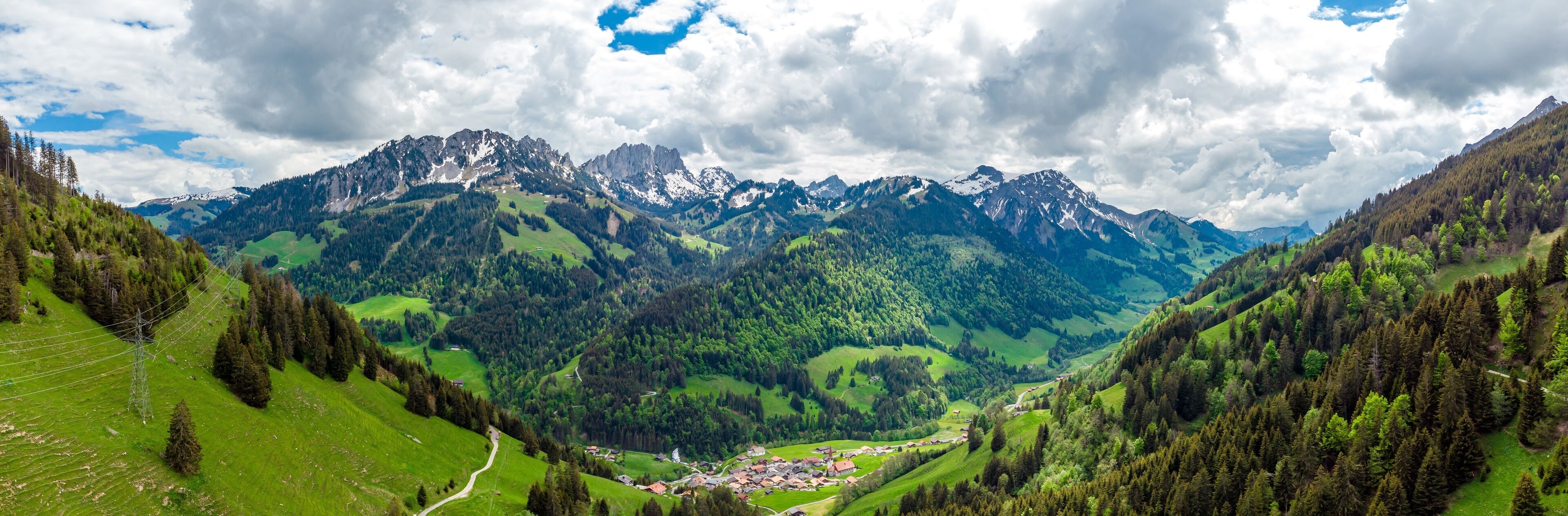 A mountainous landscape with a valley, green fields, and a small village.