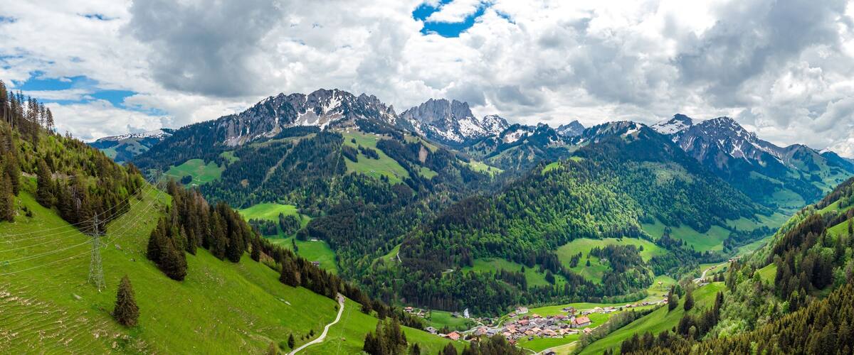 A mountainous landscape with a valley, green fields, and a small village.