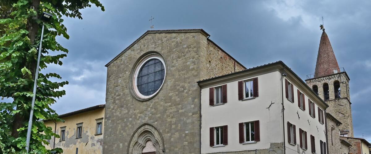 A historic building with a large circular window and a pointed tower.