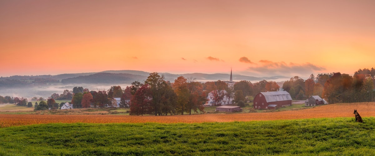 Morning breaks over Peacham, Vermont with a dog admiring the vibrant sky