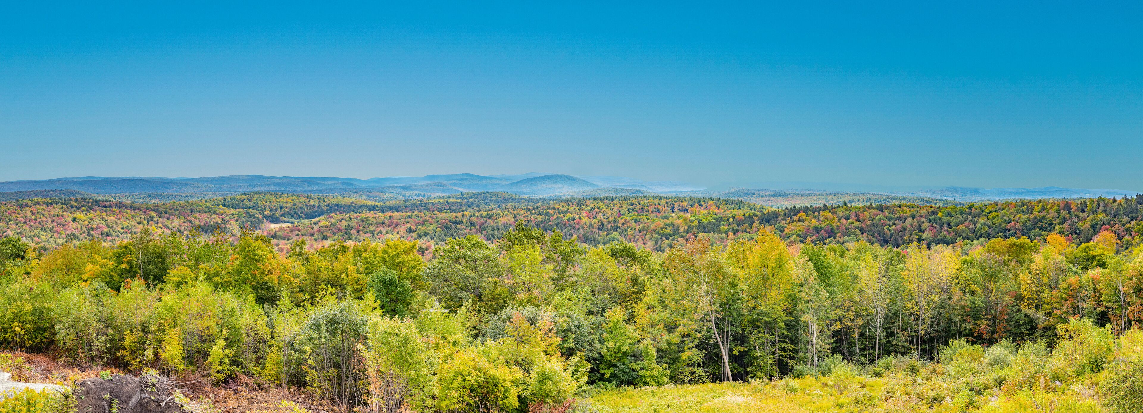 A forested mountain range with autumn foliage.