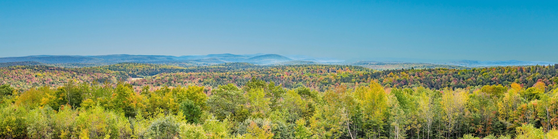 A forested mountain range with autumn foliage.
