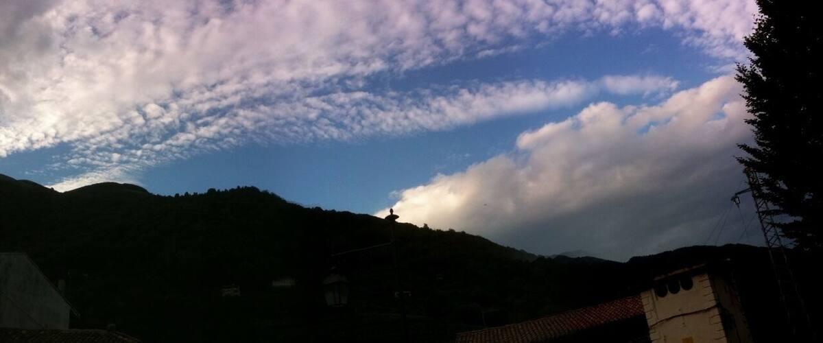 A mountainous landscape with a partly cloudy sky.