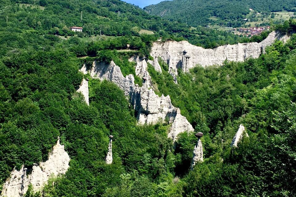A mountainous landscape with rocky cliffs and dense green forests.