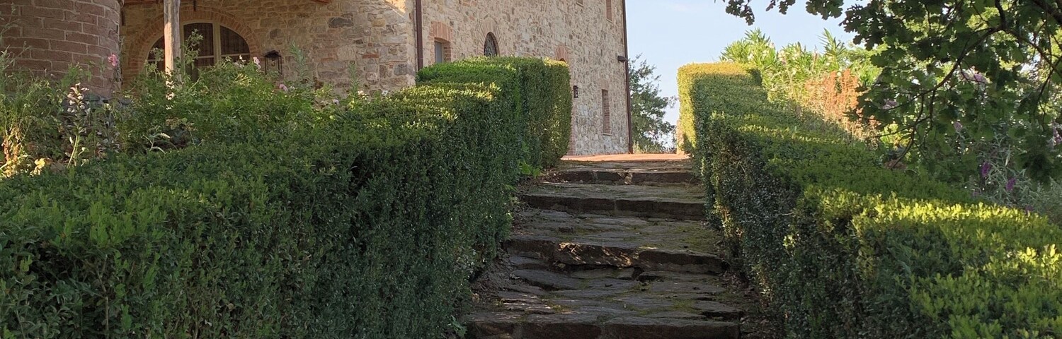 Uma escadaria de pedra leva a um edifício rodeado por sebes.