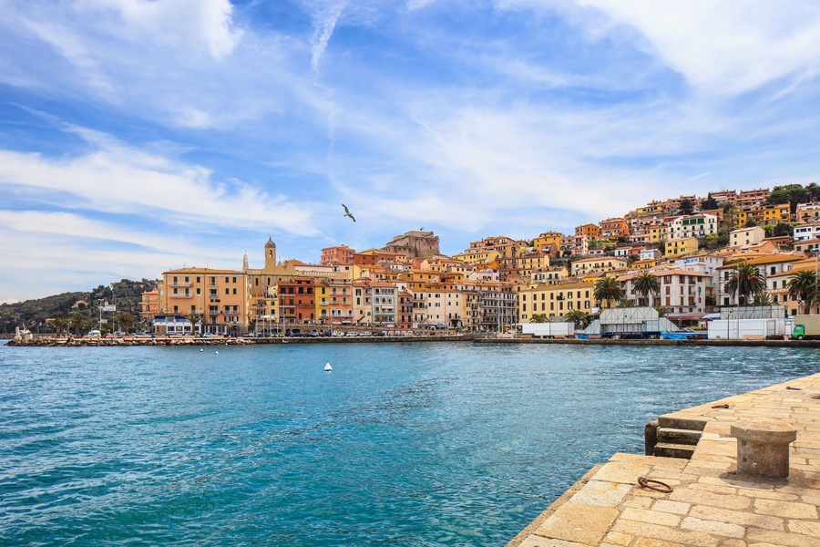 A coastal town with colorful buildings, a clear blue sky, and a calm sea.