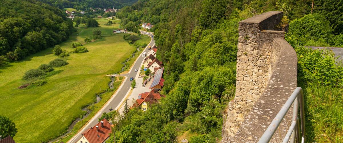 A stone wall overlooking a valley with houses and a road.