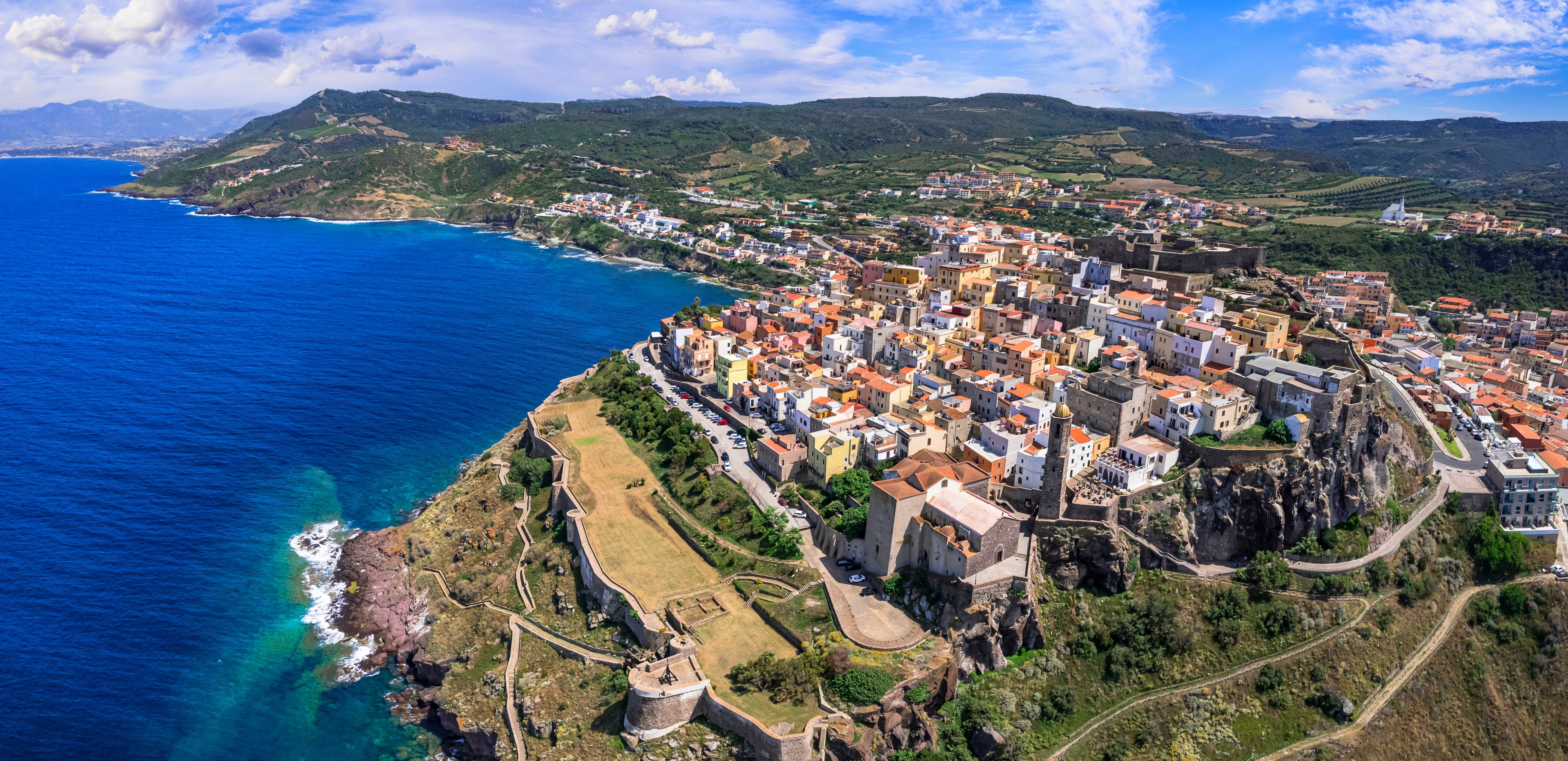 Aerial drone panoramic view of Castelsardo medieval coastal town in Sardinia. Picturesque colorful houses & historic castle in Sassari province. Authentic Italian resort architecture, north Sardegna.